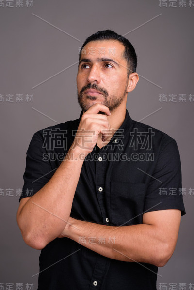 摄影棚里的波斯商人穿着黑色衬衫，背景是灰色
