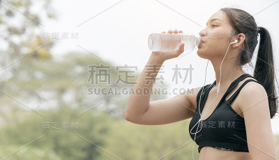 漂亮的健身女运动员在锻炼后喝水。