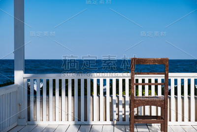 白色亭子上的棕色椅子和背景中的大海构成了一个有趣的组合