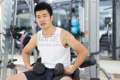 年轻英俊的男人在现代健身房健身