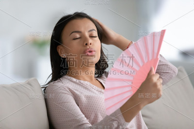 不健康的混血妇女呼吸着来自手扇的新鲜空气