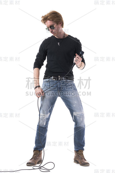 热情的年轻帅气的摇滚男歌手拿着麦克风向下看