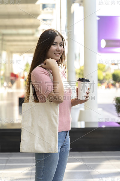 年轻漂亮的女人拿着一个白色的帆布包