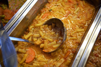 煮熟的四季豆即食。餐厅橱窗里的豆子。用勺子把即食食品盛在锅里。