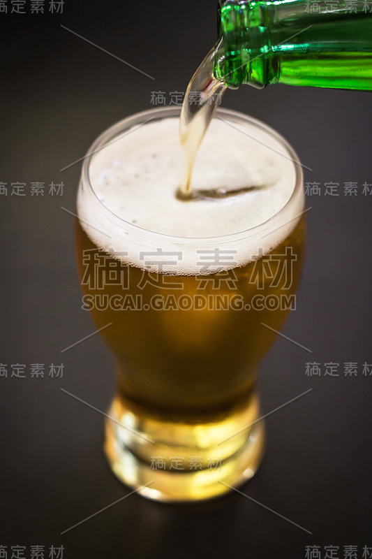 将啤酒倒进一个黑色背景孤立的高脚杯