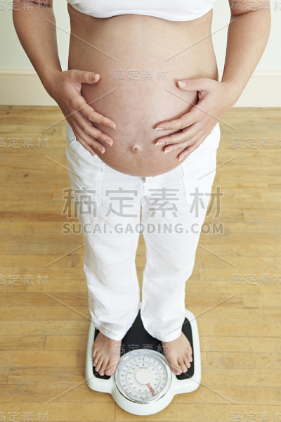 孕妇站在浴室秤上