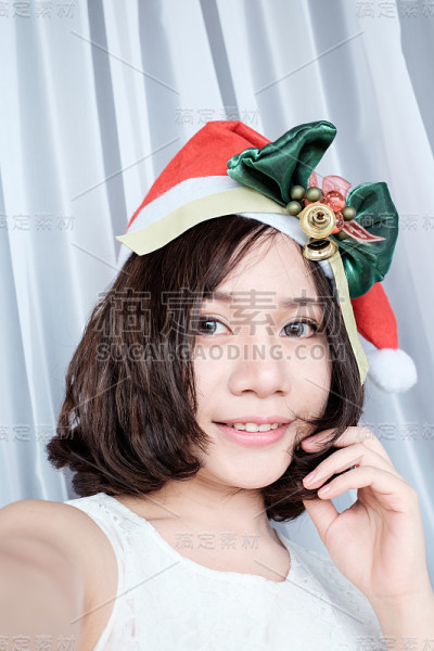 快乐美丽的女孩戴着圣诞老人帽自拍的肖像