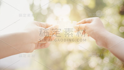 男人和女人的手连接一对拼图与光的效果。