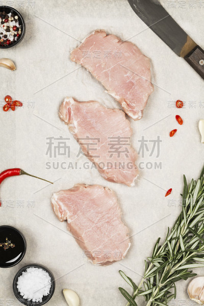 在灰色背景上放上各种香料的生肉。前视图。食品的背景
