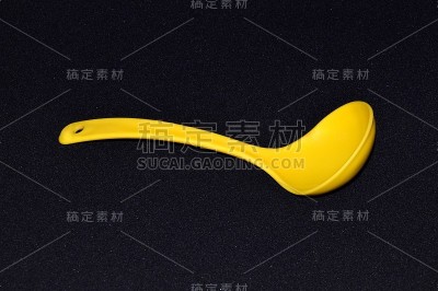 黄色塑料厨房勺子或汤勺孤立在黑色背景