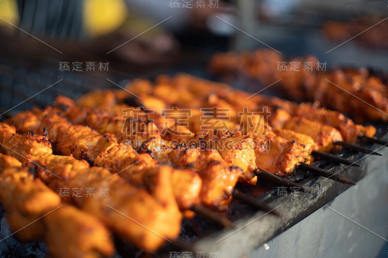 印度奶酪、鱼、鸡肉、烤鸡在露天灶台上烤着，燃烧着的煤和冒出的烟