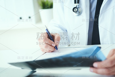 男性医生手持x光片或x光片并以医学形式做记录的特写。