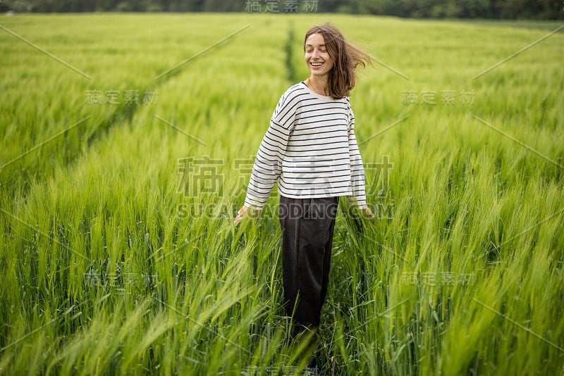 轻松的女人，站在绿色的田野，享受平静的自然