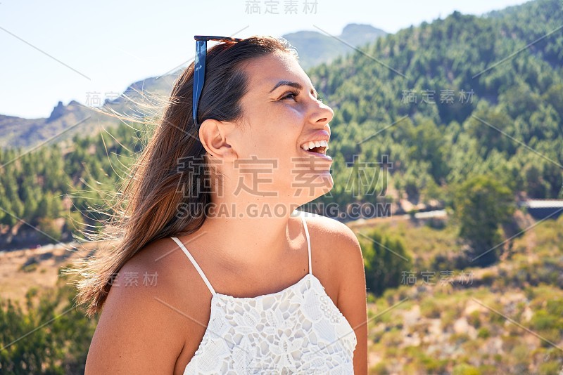 年轻美丽的女子在山上享受着暑假的风景，旅行者女孩笑得很开心