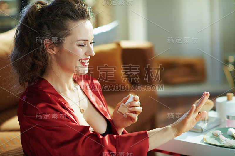 快乐时尚的家庭主妇拿着指甲油瓶子看指甲