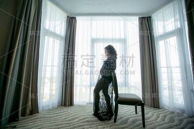 房间的窗户边有一个留着长发，穿着黑色睡衣的女人