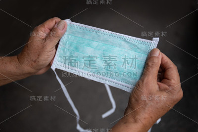 老人拿着一个绿色医用口罩
