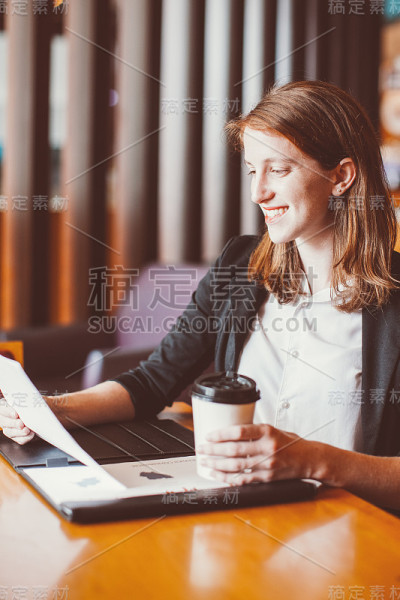 微笑的女人在咖啡馆工作和喝咖啡