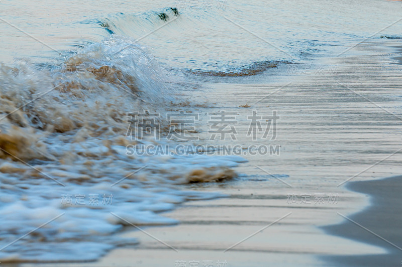 海浪在海边翻滚过棕色的沙滩