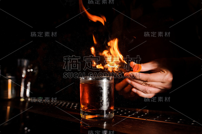 深色吧台上放着一杯烈性鸡尾酒