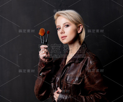 金发女人穿着邋遢夹克，拿着刷子