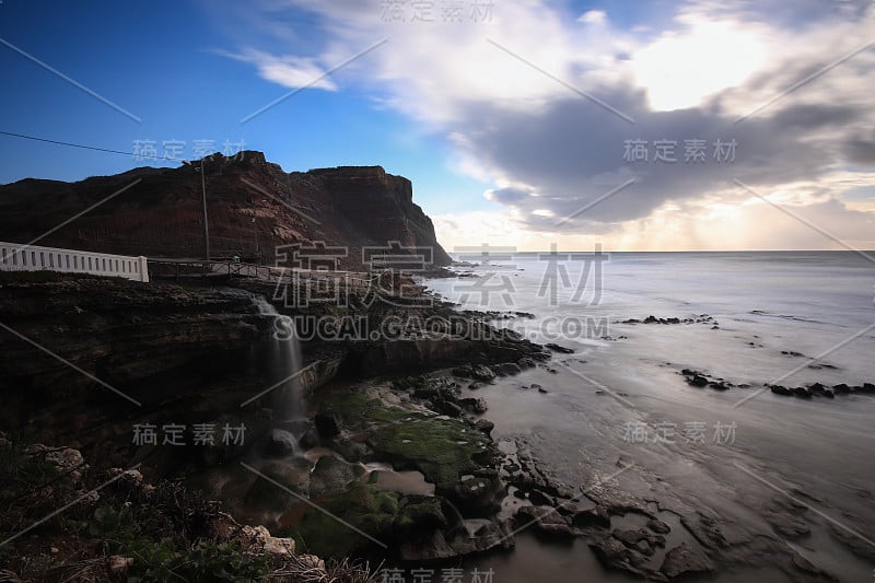 日落时分，一条海岸线上的瀑布直冲大海。长时间的曝光。葡萄牙