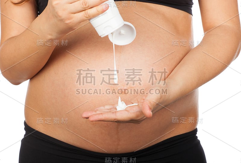 孕妇按摩她的腹部与软膏拉伸