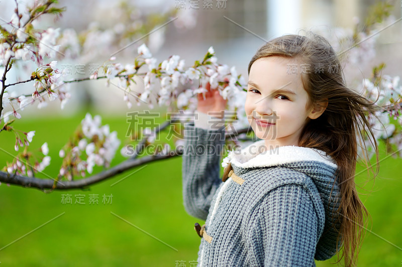 可爱的小女孩在盛开的樱桃花园里