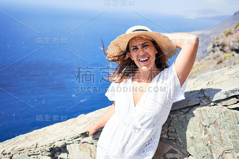 年轻美丽的女子在山上享受暑假的风景，旅行者女孩微笑着快乐的海景