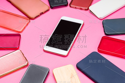 选择多色塑料手机后盖在粉红色的背景与智能手机在一边