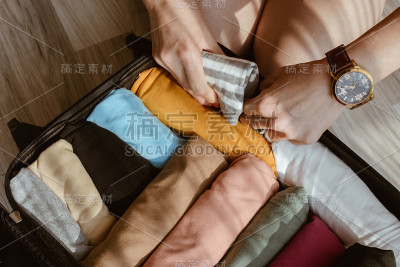 关闭的游客女子打开手提箱卷和包装彩色的布旅行。
