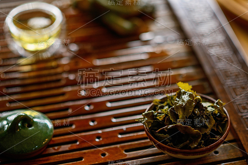 把中国乌龙茶的叶子泡在茶板上的杯子里。茶道。软的焦点。