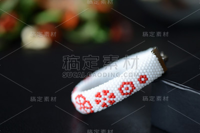 白色手镯与红色花朵在一个黑暗的背景近距离