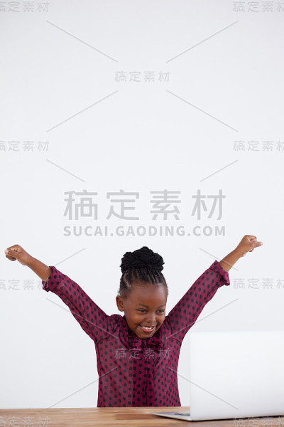 快乐的女商人举起手臂看着笔记本电脑