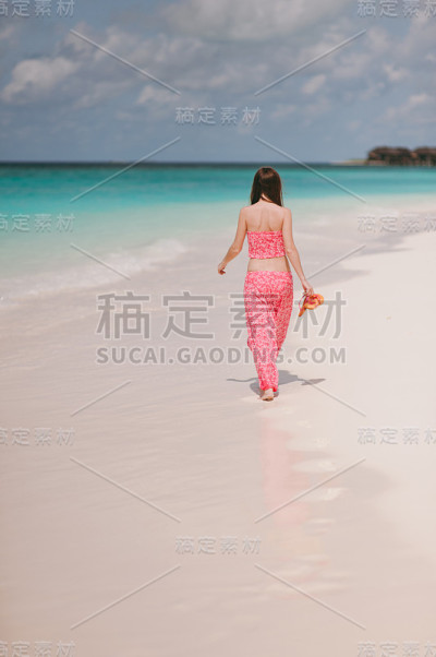 在岛的海滩上穿着粉红色衣服的女孩