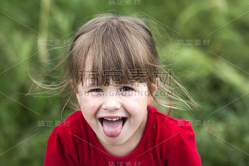 微笑的小女孩露出了舌头。年轻可爱的小女孩用嘴打手势。