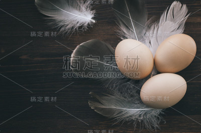 蛋壳在棕色的木质表面上，羽毛之间