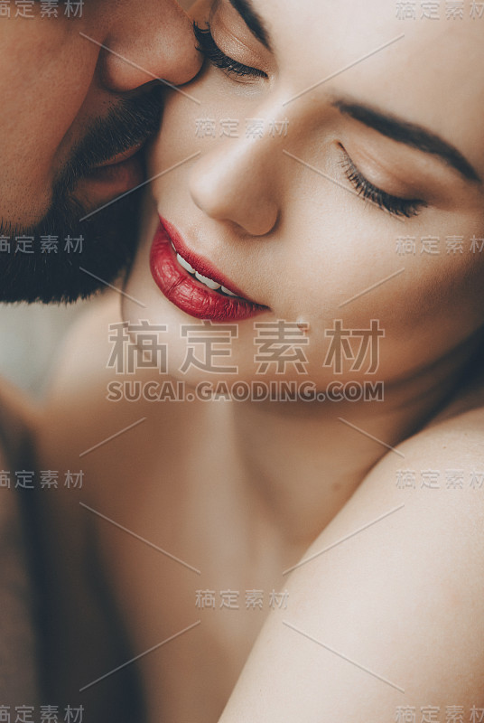 美丽的白种女孩红嘴唇被她的胡子爱人亲吻，同时拥抱对方