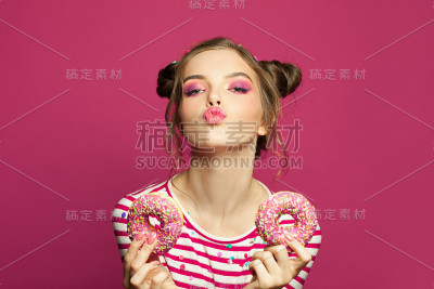 甜美有趣的女孩，粉色背景下的甜甜圈