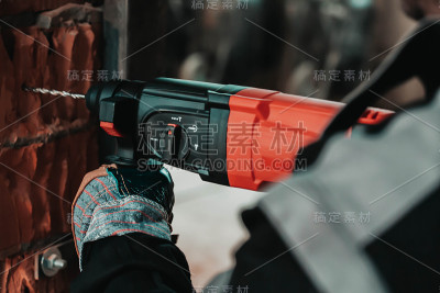 人在工作时，用大钻工把孔钻到墙上