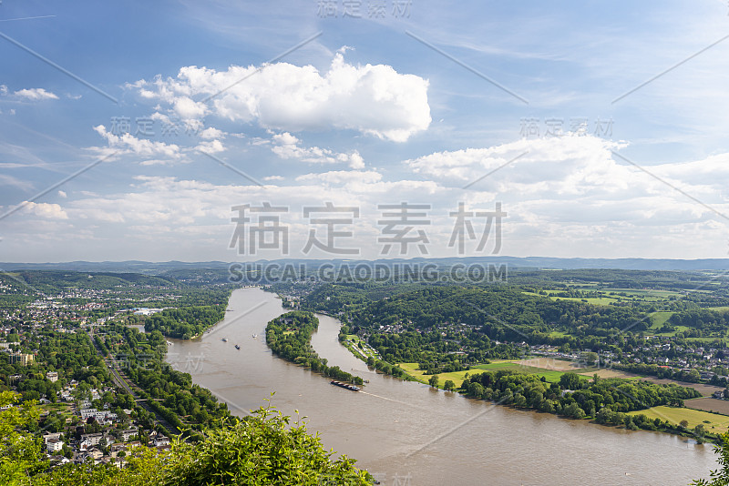 德国西部的莱茵河在天空的映衬下沿着城市流淌。河上可见驳船和船只。