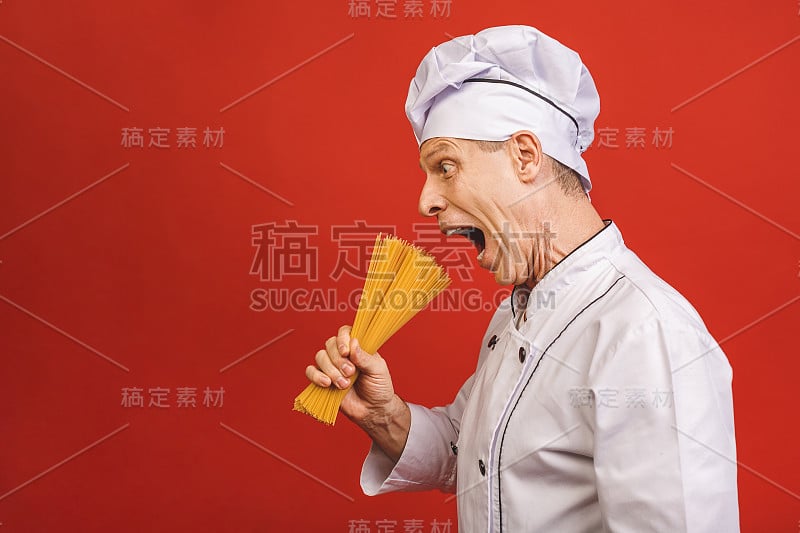 厨师手里拿着一束意大利面。餐饮和意大利食品概念孤立在红色的背景。厨师满意的脸在白色制服持有干意面。