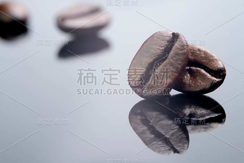 特写剪出一对烘焙咖啡豆与深棕色纹理孤立在闪亮的黑色和白色背景与阴影反射，质量巨大的颗粒饮料咖啡能量饮