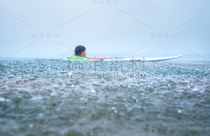 小男孩第一步冲浪者试图站在船上的热带雨