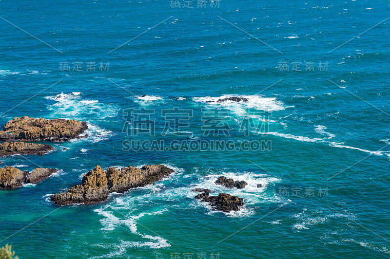 明亮的蓝色海水和白色的泡沫和岩石