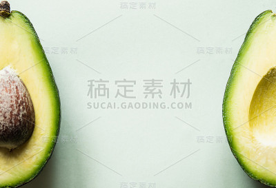 可以吃的牛油果切成两半，孤立在浅绿色的背景上