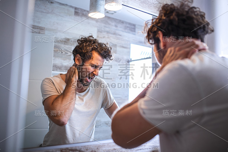 睡眼惺忪的年轻人在早上看浴室里的镜子，侧视图。试着醒来。睡眠不足，失眠，生活压力大。宿醉。抑郁症。