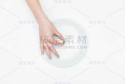 一个女人的手从盘子里取出一颗绿豌豆