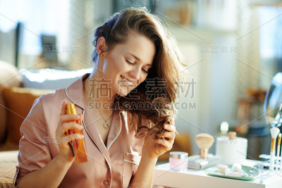 快乐的女人拿着发油，检查发梢