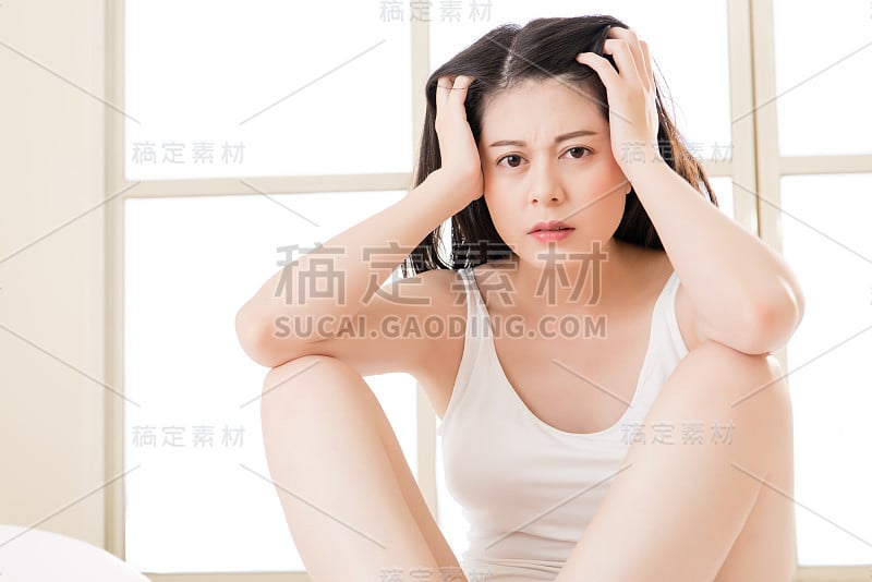 美丽的亚洲女人遭受头痛和按摩额头